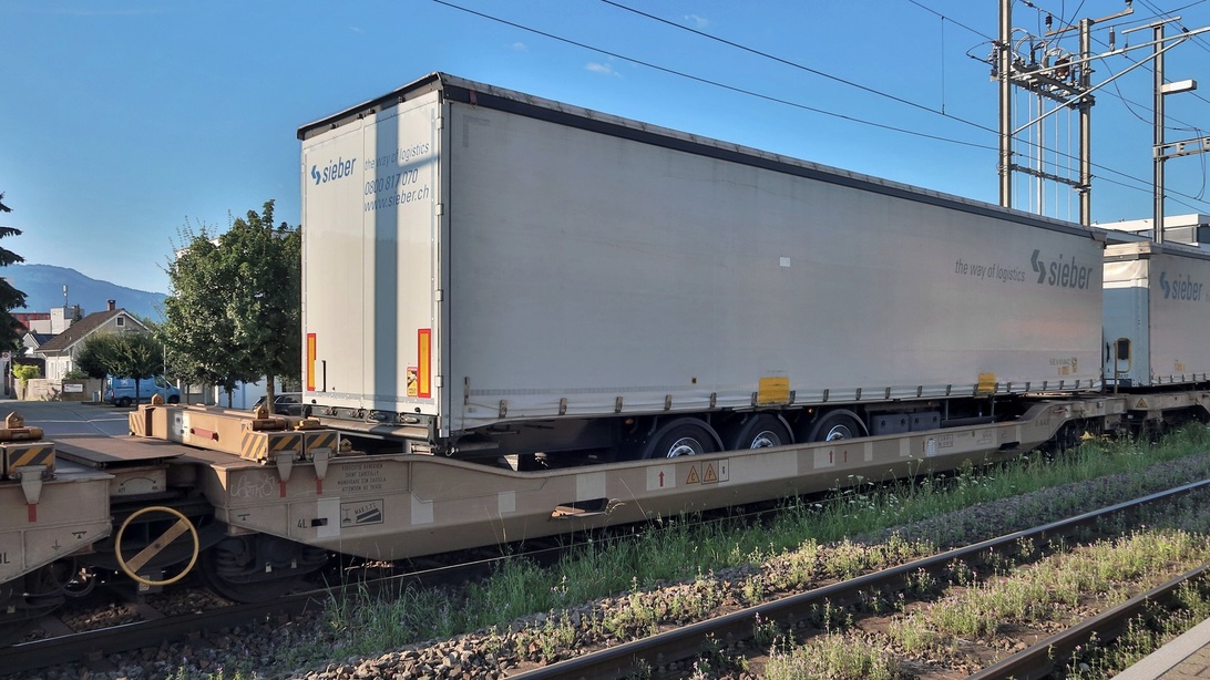 Ein LKW-Auflieger der Marke 'Sieber' wird auf einem Flachwagen eines Güterzugs transportiert.