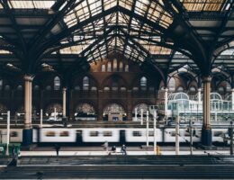 Historische Bahnhofshalle mit Stahltragwerk und vorbeifahrendem Zug