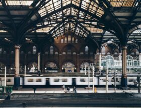 Historische Bahnhofshalle mit Stahltragwerk und vorbeifahrendem Zug