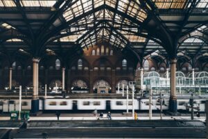 Historische Bahnhofshalle mit Stahltragwerk und vorbeifahrendem Zug