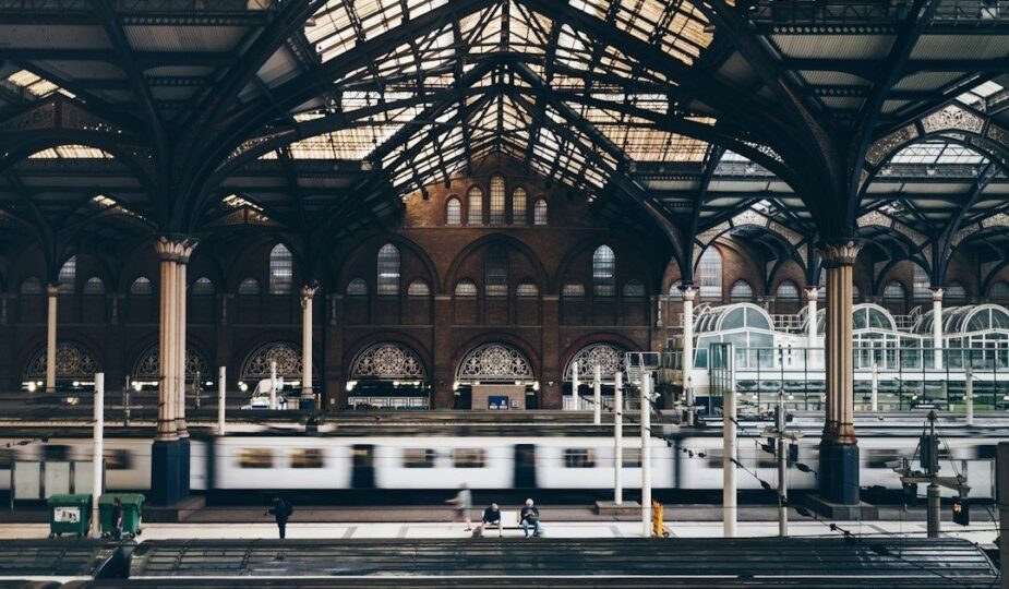 Historische Bahnhofshalle mit Stahltragwerk und vorbeifahrendem Zug