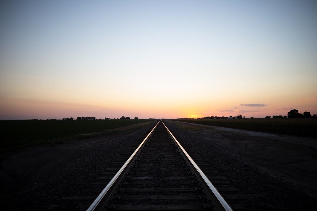Gerade Bahnstrecke führt bei Sonnenuntergang durch ländliche Felder
