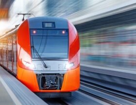 Moderner orange-roter Regionalzug fährt an einem Bahnsteig ein