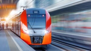 Moderner orange-roter Regionalzug fährt an einem Bahnsteig ein