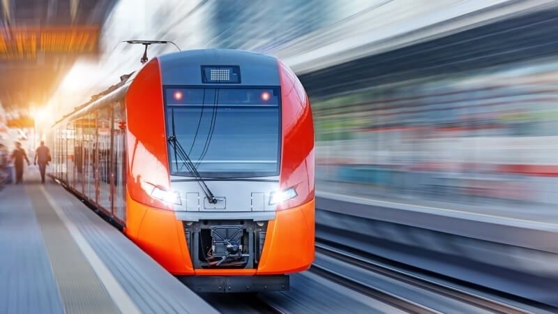 Moderner orange-roter Regionalzug fährt an einem Bahnsteig ein