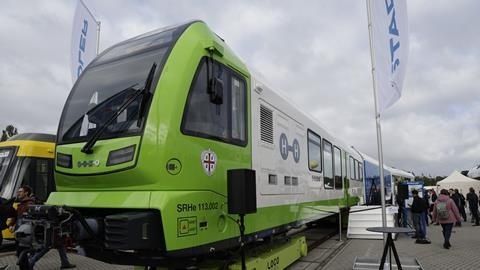 Grüner Wasserstoffzug auf einer Messeplattform unter bewölktem Himmel